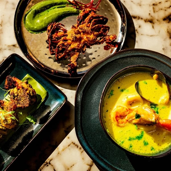 Three Indian seafood dishes: fried calamari, grilled prawns, and a yellow seafood curry.