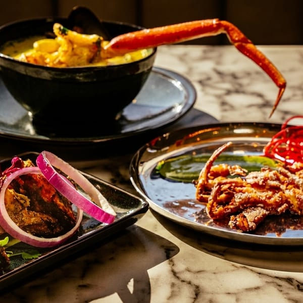Three plates of seafood dishes, including crab curry, fried soft-shell crab, and grilled prawns.